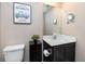 Half bathroom with white countertop, dark cabinets, toilet, and mirror with picture on the wall at 5424 Companion Ln, Tampa, FL 33619