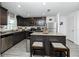 A modern kitchen features dark cabinetry, stainless steel appliances, a granite island, and wood-look flooring at 5424 Companion Ln, Tampa, FL 33619