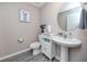 Cozy powder room featuring stylish gray wood floors, pedestal sink, and a decorative round mirror at 5424 Companion Ln, Tampa, FL 33619