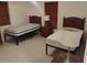 Neutral bedroom featuring twin beds, tile flooring, and a side table with a lamp at 5905 Cleveland Dr, Punta Gorda, FL 33982