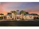 Exterior view of community clubhouse with palm trees, landscaping, and a beautiful sunset at 6042 Jensen View Ave, Apollo Beach, FL 33572