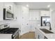 Bright kitchen with stainless steel appliances, white cabinetry, center island, and wood-look tile flooring at 6046 Jensen View Ave, Apollo Beach, FL 33572