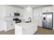 Modern kitchen features white cabinets, stainless steel appliances, a large island, and stylish wood flooring at 6046 Jensen View Ave, Apollo Beach, FL 33572