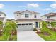 Two-story home showcasing a two-car garage, blue front door, well-manicured lawn, and vibrant landscaping at 6058 Jensen View Ave, Apollo Beach, FL 33572
