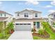 This exterior shows a two-story home featuring a two-car garage, blue front door, and vibrant landscaping at 6058 Jensen View Ave, Apollo Beach, FL 33572