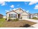 Charming single-Gathering home featuring neutral paint, a two-car garage, and a well-manicured front lawn on a sunny day at 16750 Sunburst Lake St, Wimauma, FL 33598
