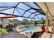 Scenic outdoor pool area with screened-in lanai, patio furniture, and serene water view at 5497 56Th E Ct, Bradenton, FL 34203