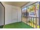 Screened-in balcony featuring synthetic grass flooring, white textured walls and a view of palm trees at 5151 Puritan Cir # 1022, Tampa, FL 33617