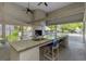 Well-equipped outdoor kitchen features a fireplace, granite countertops, sink, and ceiling fans for comfortable entertaining at 5151 Puritan Cir # 1022, Tampa, FL 33617