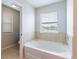 Bright bathroom showcasing a soaking tub with tile surround and natural light from the window at 2746 Walden Woods Dr, Plant City, FL 33566