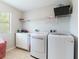 Bright laundry room equipped with modern washer and dryer, counter space, and overhead storage shelves at 2746 Walden Woods Dr, Plant City, FL 33566