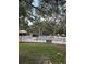 Community pool area surrounded by mature trees and a white picket fence with sun umbrellas and lounge chairs at 870 Virginia St # 108, Dunedin, FL 34698