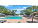 Community pool surrounded by mature trees, lounge chairs, and shade umbrellas at 2700 Coconut Bay Ln # 419, Sarasota, FL 34237