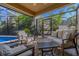 Screened-in patio with stylish outdoor seating, offering a view of the lush backyard and pool at 1103 Kensington Ct, Safety Harbor, FL 34695