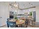 Bright kitchen boasts white cabinets, stainless appliances, stylish lighting, and a cozy breakfast nook with round table at 6288 Winding Pine Dr, Nokomis, FL 34275