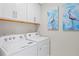 Well-equipped laundry room with white appliances, white cabinets, and stylish decor at 6288 Winding Pine Dr, Nokomis, FL 34275