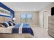 Bright main bedroom boasts blue accent wall, modern decor, and plush king bed with direct access to an ensuite bathroom at 6288 Winding Pine Dr, Nokomis, FL 34275