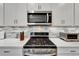 Close-up of a kitchen with stainless steel gas range, microwave, white cabinets and decorative tile backsplash at 19165 Iron Topsail Isle, Land O Lakes, FL 34638