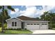 Charming one-story home featuring a three-car garage, gray stucco, and stone veneer accents at 9211 Players Dr, Weeki Wachee, FL 34613