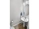Elegant half-bathroom features a pedestal sink, oval mirror, modern lighting and fixtures, and wood-look flooring at 5367 Riverwalk Preserve Dr, New Port Richey, FL 34653