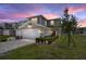 Charming two-story townhome featuring an attached two-car garage and beautifully maintained front yard at dusk at 5367 Riverwalk Preserve Dr, New Port Richey, FL 34653
