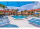Community pool and lounge area with chairs, tables, and umbrellas surrounded by lush landscaping and building views at 10365 Paradise Blvd # 21, Treasure Island, FL 33706