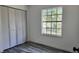 This bedroom features a window, wood-look tile flooring, and a closet with folding doors at 4546 Ontario Dr, New Port Richey, FL 34652
