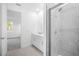 Modern bathroom with glass-enclosed shower, white vanity, and access to a bright adjacent room at 9127 Players Dr, Weeki Wachee, FL 34613