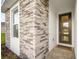 The front door of a single-story home with gray stone and white accents with gray brick at 9127 Players Dr, Weeki Wachee, FL 34613