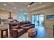 Cozy living room with a comfortable leather sofa, tile flooring, and seamless access to the outdoor pool area at 14553 Eagle Branch Dr, Nokomis, FL 34275