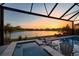 Screened-in pool and hot tub with a beautiful sunset and water view, ideal for relaxing evenings at 14553 Eagle Branch Dr, Nokomis, FL 34275