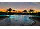 Stunning pool at sunset with swaying palm trees and vibrant sky reflecting in the water at 14553 Eagle Branch Dr, Nokomis, FL 34275