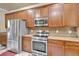 Modern kitchen with stainless steel appliances, wood cabinets, and tile backsplash at 6932 Gray Catbird Loop, Wesley Chapel, FL 33545