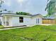 Back exterior view features a covered patio, grassy yard, and privacy fence, offering a private outdoor space at 801 Leeward Way, Palm Harbor, FL 34685