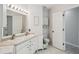 Well-lit bathroom with double sinks, white cabinets, framed mirror, and private toilet area at 1061 Pinellas Bayway S, Tierra Verde, FL 33715