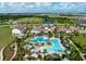 Overhead view of a large outdoor swimming pool with plenty of lounge chairs and umbrellas with surrounding homes at 3255 Hilltop Cir, Bradenton, FL 34211