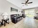 Living room boasts a leather couch, ceiling fan and sliding glass doors to backyard patio at 1718 Trailwater St, Ruskin, FL 33570