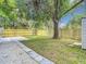 This backyard view showcases a new wood fence, lush green lawn, mature shade trees, and a useful storage shed at 4202 W Bay Vista Ave, Tampa, FL 33611