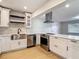 Open kitchen with stainless steel appliances, white cabinets, and light granite countertops at 4202 W Bay Vista Ave, Tampa, FL 33611