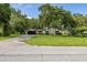 Wide view of charming single-story home with stone accent and mature shade trees on a verdant lawn at 4401 W Sam Allen Rd, Plant City, FL 33565