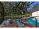 Enclosed pool and hot tub with brick accents and views of the spacious, tree-lined yard at 4401 W Sam Allen Rd, Plant City, FL 33565