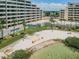 Aerial view of a beach area near apartments and the bay, with seating and palms at 6009 Sea Ranch Dr # 203, Hudson, FL 34667