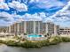 Exterior of a building near a pool surrounded by lush greenery and palm trees at 6009 Sea Ranch Dr # 203, Hudson, FL 34667