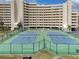 Outdoor tennis courts for residence use with nearby condo building on a sunny day at 6009 Sea Ranch Dr # 203, Hudson, FL 34667