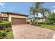 Charming home with a brick driveway, two-car garage, lush landscaping, and stately palm trees at 17109 Kenton Ter, Bradenton, FL 34202