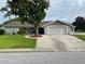 Charming single-story home featuring a well-maintained lawn, mature tree, and an attached two-car garage at 12215 Cobble Stone Dr, Hudson, FL 34667