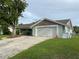 View of a single-story house showing the front yard with a long driveway and green grass at 12215 Cobble Stone Dr, Hudson, FL 34667