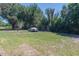 Open grassy backyard with covered vehicle and mature trees at 3736 Lado Dr, Wesley Chapel, FL 33543