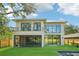 Back exterior featuring screened-in patio, modern balcony, and view of manicured lawn at 1630 Douglas Ave, Dunedin, FL 34698