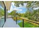 View from the balcony of a private yard with a pool and landscaping on a sunny day with blue skies and white clouds at 1630 Douglas Ave, Dunedin, FL 34698